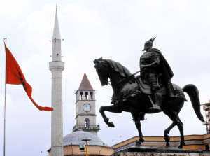 Koti, uskonto ja isänmaa. Albanian kotkalippu, Et'hem Beyn moskeija ja kansallissankari Skanderbegin patsas.